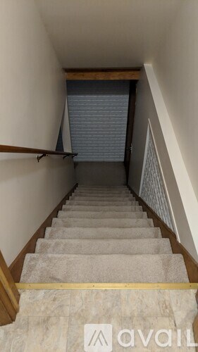 A staircase with a wooden handrail and a carpeted runner.