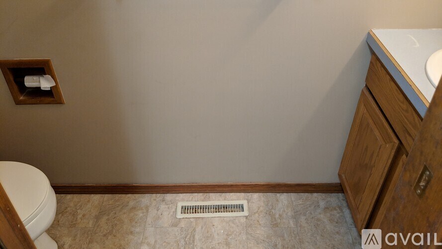 A bathroom with a toilet, a sink, and a wooden cabinet.
