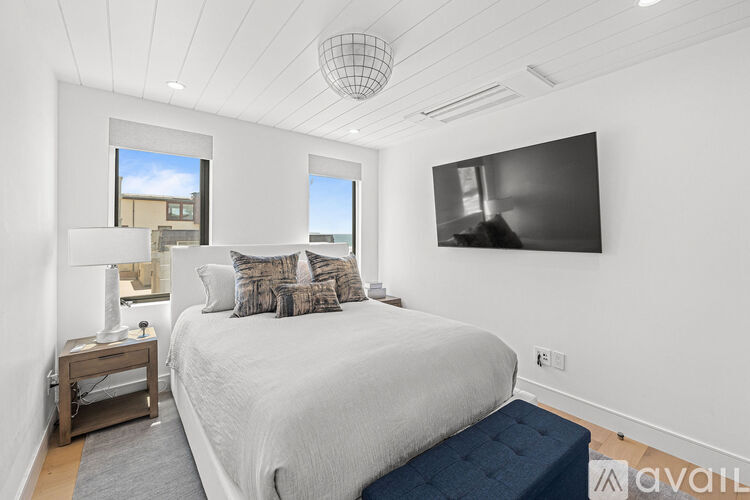 A bedroom with a large bed, a nightstand with a lamp, and a window with a view of a building outside.