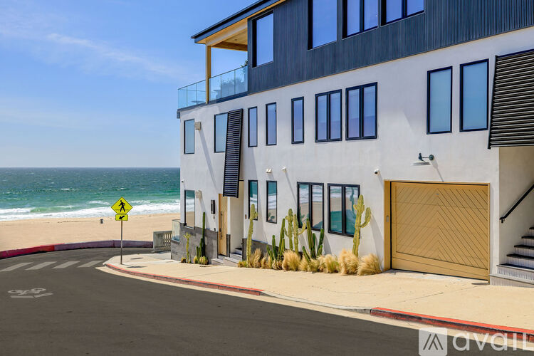 A modern building with a balcony overlooking the beach.