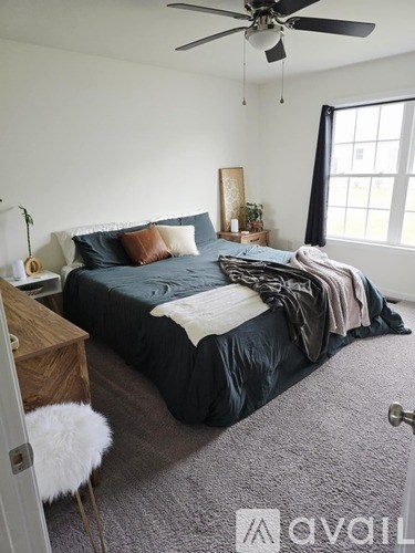 A bedroom with a bed, a dresser, and a ceiling fan.