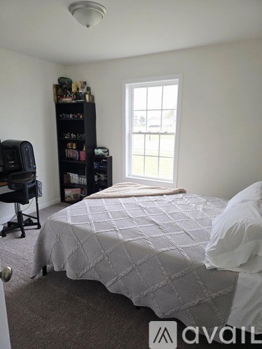 A bedroom with a bed, a desk, and a window.