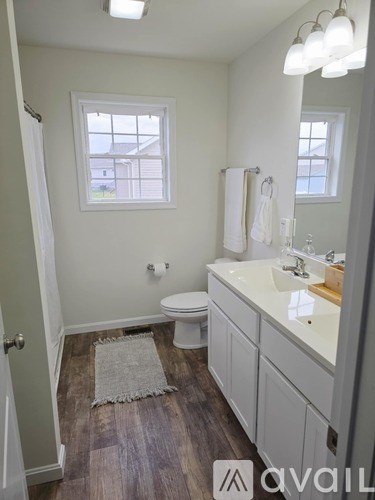 A bathroom with a toilet, sink, and window.