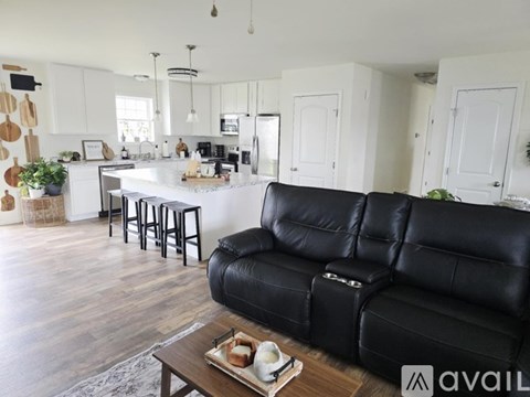 A black leather sofa sits in a well-lit kitchen and living room.