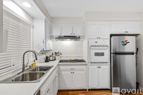 A kitchen with white cabinets and a silver refrigerator.