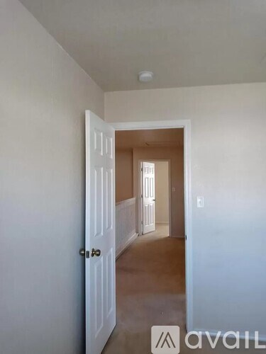 A hallway with a door on the left and a window in the distance.