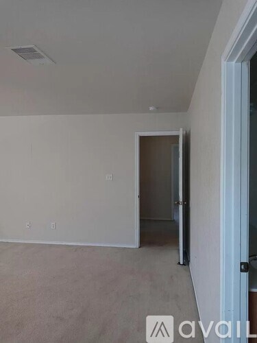 A room with a carpeted floor and a door on the right side.