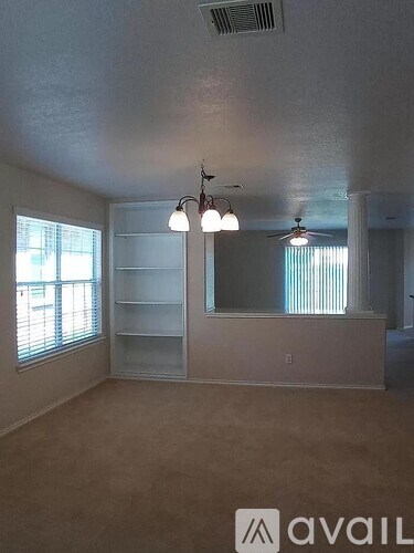 A room with a ceiling fan and a large window.