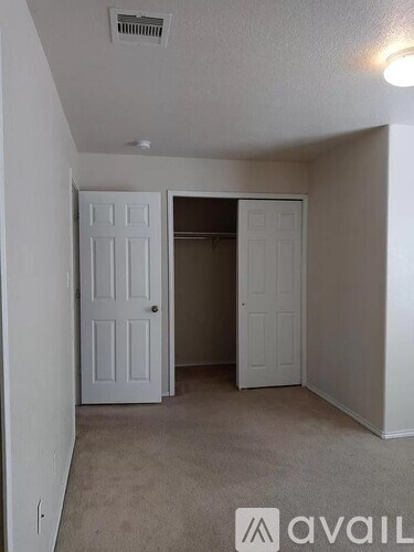A room with a carpeted floor and two doors, one of which is open.