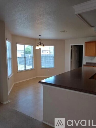A kitchen with a brown counter top and a chandelier hanging from the ceiling.