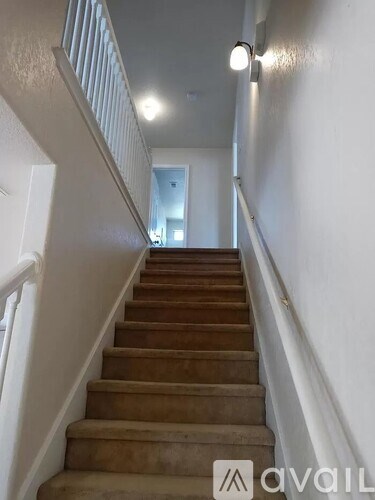 A staircase with a white railing and wooden steps leading to a doorway.