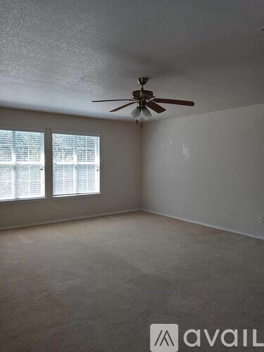 A room with a ceiling fan and two windows.