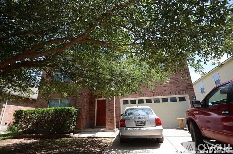 A house with a tree in front and two cars parked in front of it.
