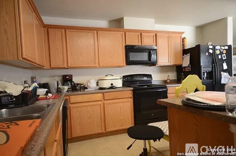 A kitchen with wooden cabinets and a black fridge.
