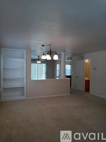 A large empty room with a refrigerator and a few shelves.