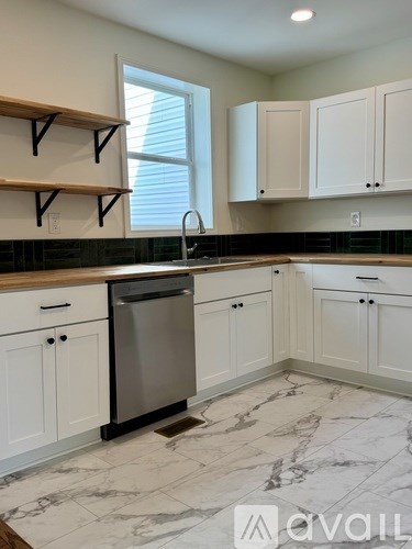 A kitchen with white cabinets and a marble floor.