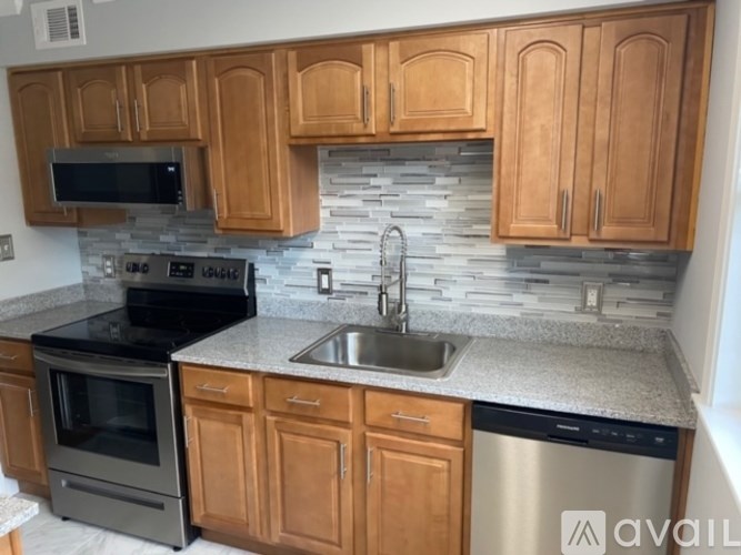 A kitchen with wooden cabinets and a stone backsplash.