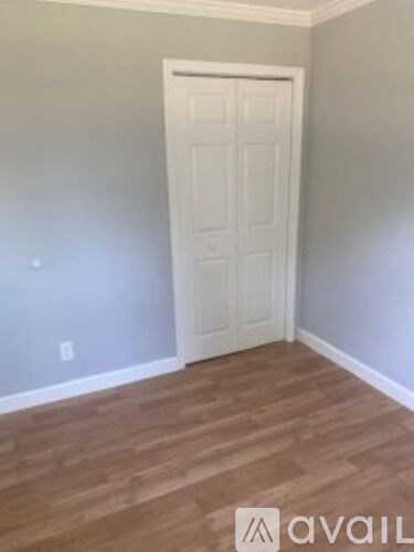 A room with a white door and wooden flooring.