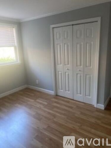 A room with a white door and wooden flooring.