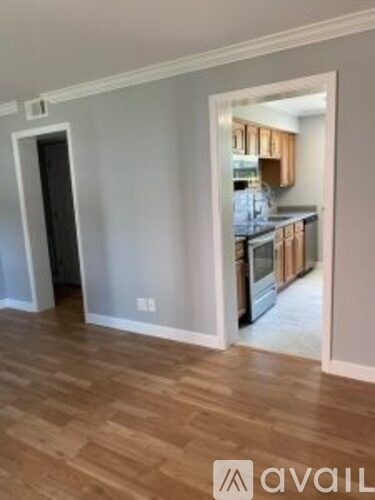 A kitchen with wooden cabinets and a countertop is visible through a doorway.