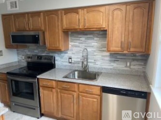 A kitchen with wooden cabinets and a stone backsplash.