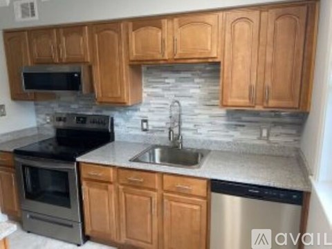 A kitchen with wooden cabinets and a stone backsplash.