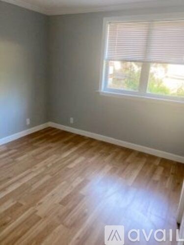 A room with wooden flooring and a window with blinds.