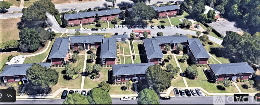 A large building complex with multiple red buildings and a parking lot in front.