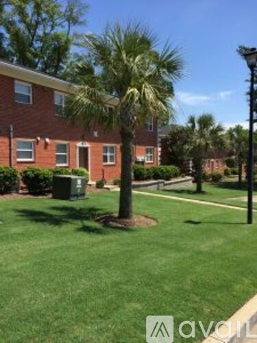 A palm tree stands in front of a brick building.