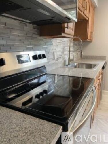 A modern kitchen with a black stove top oven and a stone backsplash.