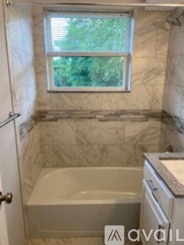 A bathroom with a tub, sink, and window.