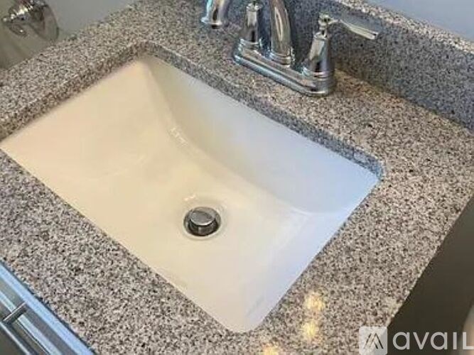 A bathroom sink with a granite countertop and a chrome faucet.