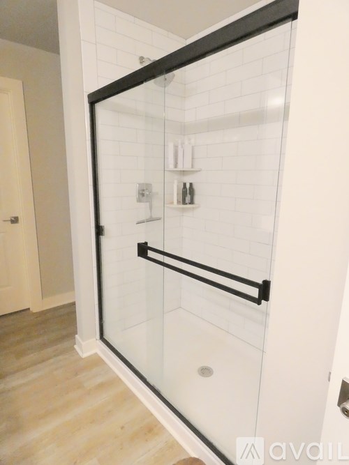 A bathroom with a glass shower door and white tiles.