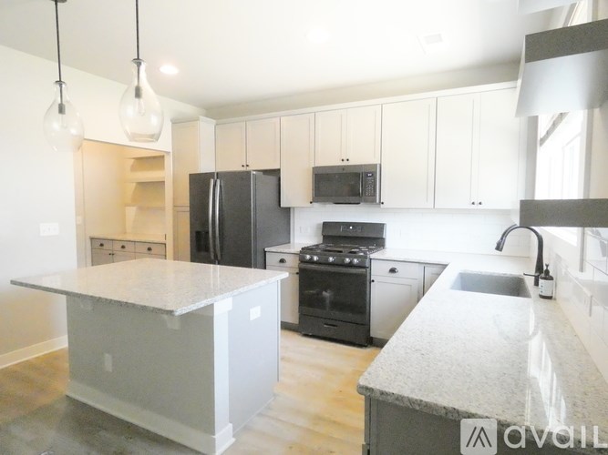 A kitchen with a white island and black appliances.