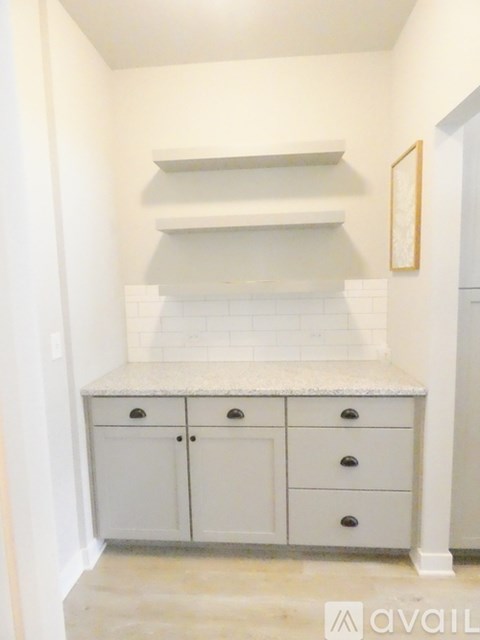 A kitchen with white cabinets and a marble countertop.