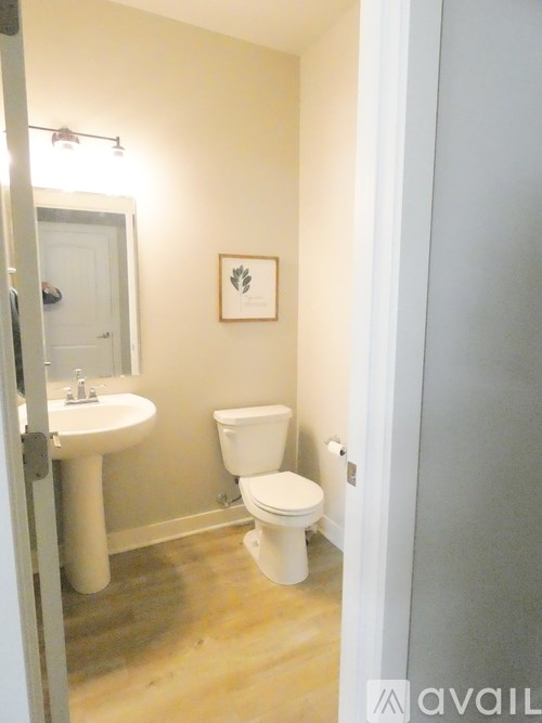 A bathroom with a toilet, sink and mirror.