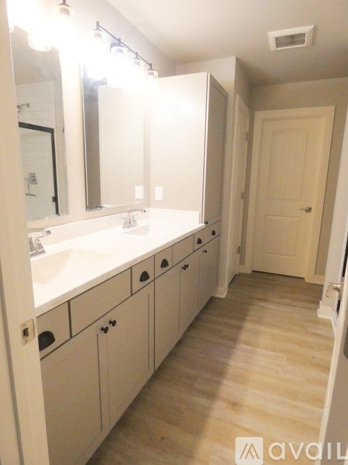 A bathroom with a sink, mirror, and wooden floors.
