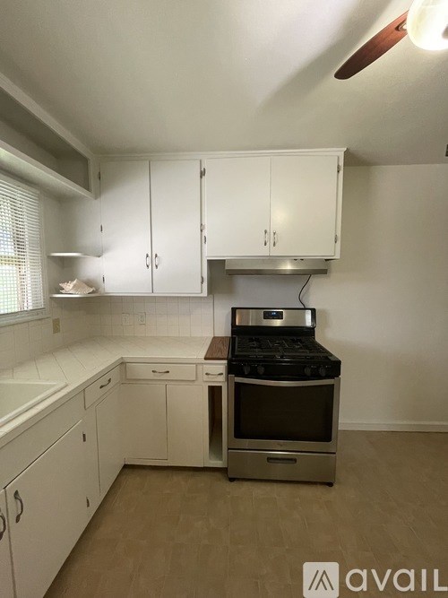 A kitchen with white cabinets and a stove top oven.