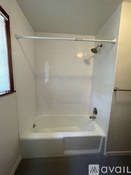 A white bathroom with a tub and a shower head.