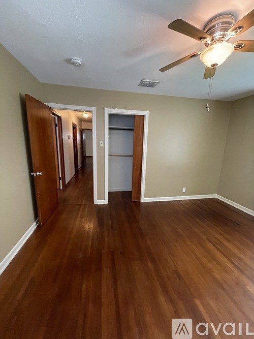 A room with a ceiling fan and wooden floors.