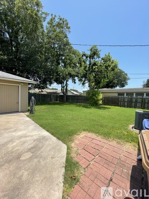 A backyard with a concrete path and a brick border.