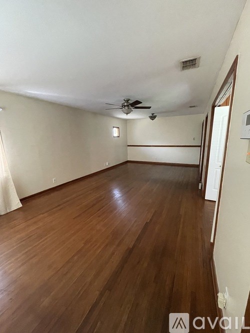 A room with wooden flooring and a ceiling fan.