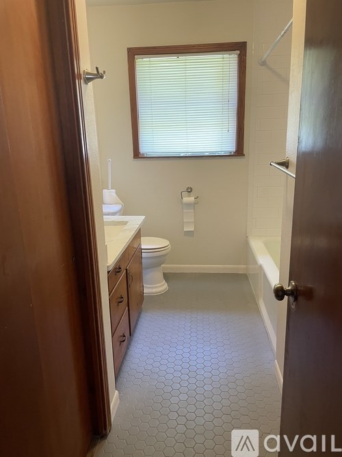 A bathroom with a toilet, sink, and a window.
