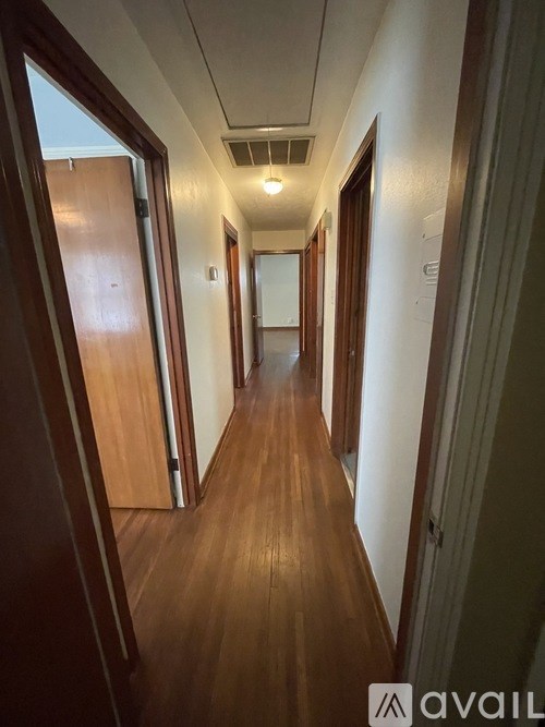 A long hallway with wooden floors and doors on both sides.