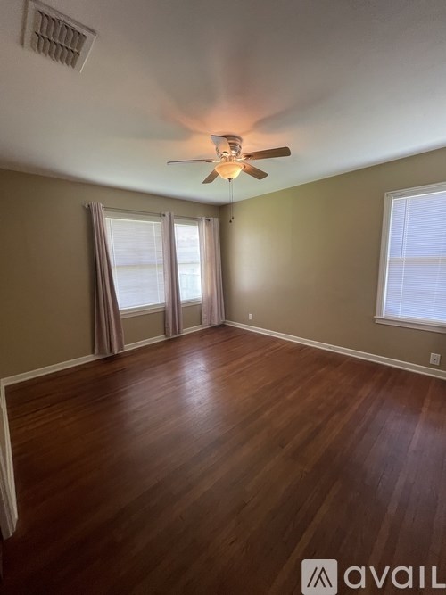 A room with a ceiling fan and wooden flooring.