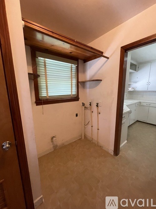 A bathroom with a window and a door leading to a kitchen.