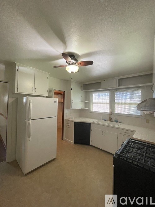 A kitchen with a white fridge and black stove top.