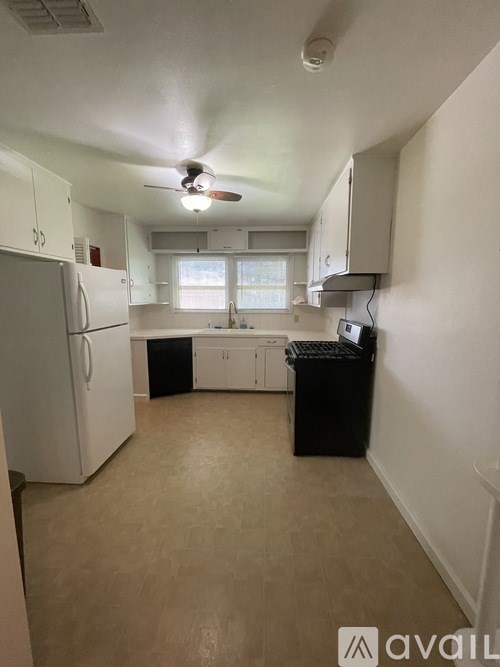 A kitchen with white cabinets and a black trash can.