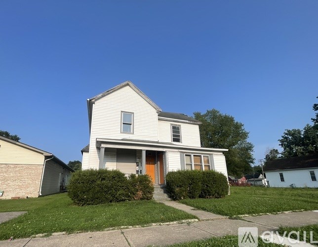 A two-story house with a front porch and a brown door.