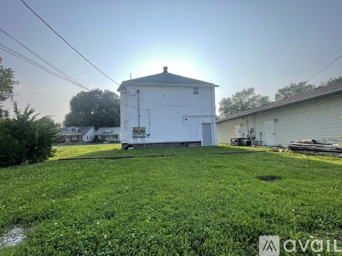 A white barn sits in a grassy field with a clear sky above.